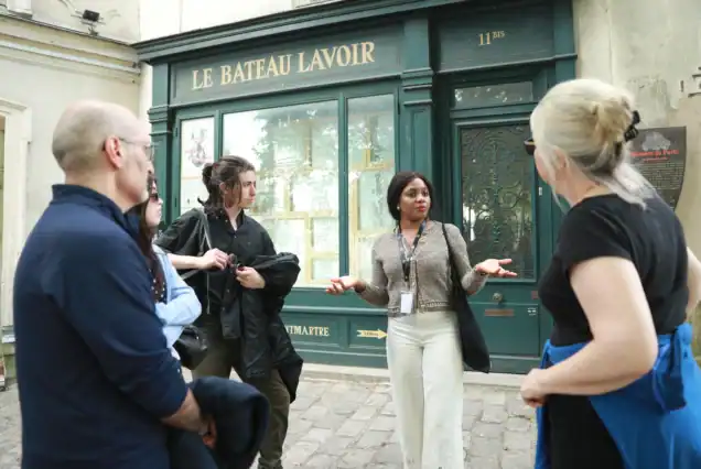 Client group listening to guide stories during Montmartre walking tour with Sacré-Cœur visit