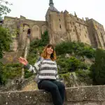 Traveler posing with Mont Saint Michel abbey in background during private day trip from Paris
