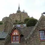 Mont Saint Michel abbey and village rooftops seen from the bay on a guided day trip from Paris