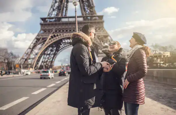 Private Paris tour guide leading travelers through Paris near Eiffel Tower on a sunny day